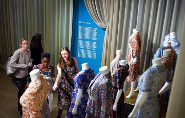 Image of 3 people looking at clothing on display a the Fashion and Textile Museum