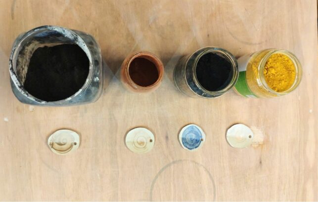 Image shows different samples of colouring substances for ceramic works. They are shown painted on small pieces of clay.