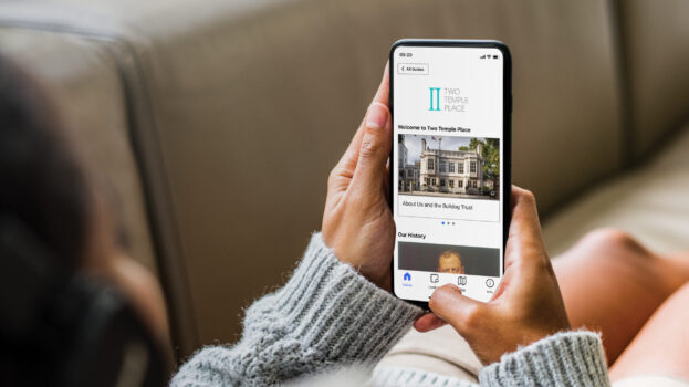 Two hands holding mobile phone with Welcome page of Twp Temple Place's digital guide on screen